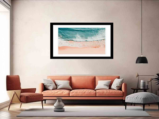 Framed beach scene art print on a wall above an orange sofa in a living room.
