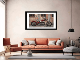Framed picture of a motorcycle on a wall above an orange sofa in a living room.