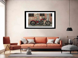 Framed picture of a red motorcycle on a wall above an orange sofa in a living room.
