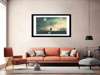 Framed artwork of a person walking in a scenic landscape above an orange sofa in a living room.