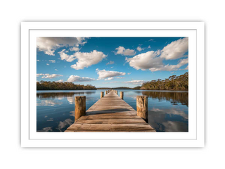 Wooden dock extending into a calm lake with a blue sky and clouds.
