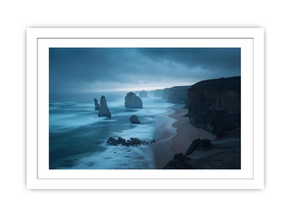 Framed artwork of a coastal scene with rocks and water at dusk.