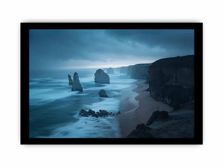 Framed artwork of a coastal landscape with cliffs and ocean under a stormy sky.
