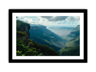 Framed photograph of a mountainous landscape with greenery and a clear sky.