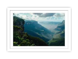 Framed photograph of a mountainous landscape with greenery and a cloudy sky.