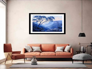 Framed artwork of a mountain landscape above an orange sofa in a living room.