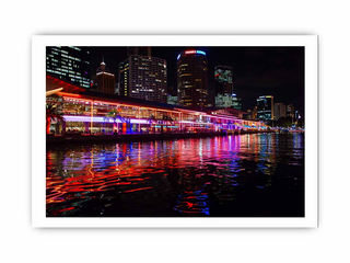 City skyline at night with illuminated buildings reflected in water