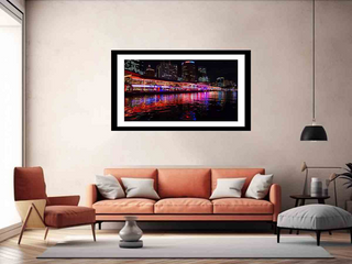 Framed artwork of a cityscape over water in a living room with a sofa and chairs.