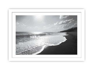 Black and white framed photograph of a beach with waves and a cloudy sky.