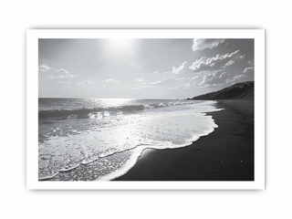 Black and white beach scene with waves and a cloudy sky