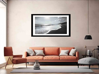 Framed artwork of a beach scene above an orange sofa in a living room.