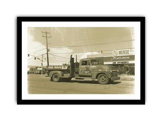 Vintage truck parked in front of a store with a clear sky.