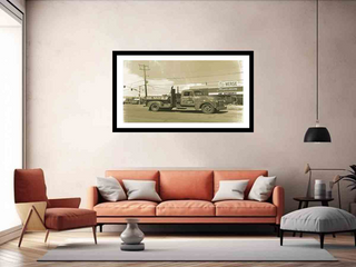 Framed black and white photo of a truck on a wall above an orange sofa in a living room.