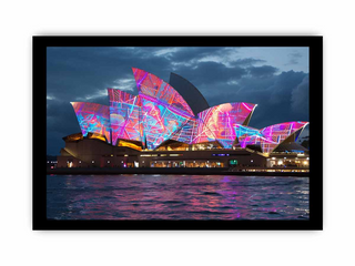 Sydney Opera House with colorful lights at night, reflected in the water.