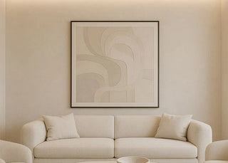 Modern living room with beige sofa, coffee table, and abstract art on wall.