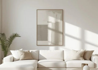 A modern white sectional sofa in a bright, minimalist living room with light wood flooring, a white rug, and a large abstract wall art piece.