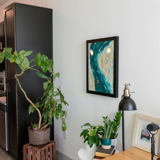 Modern interior with plants, a black lamp, and framed artwork on a white wall.